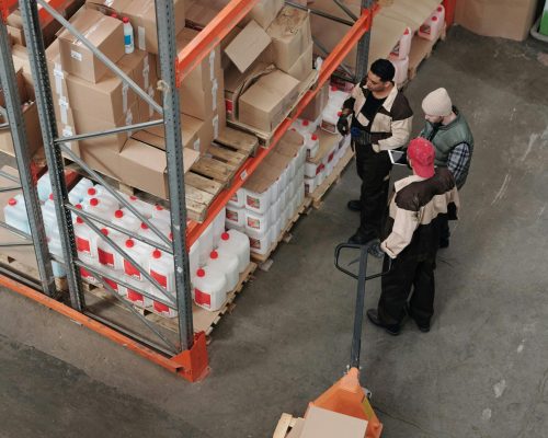 Three warehouse workers discussing inventory organization details.